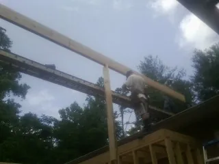 Carpenter setting a ridge beam over a new addition frame — Ice Dam Removal by Roofing Brothers in Roswell