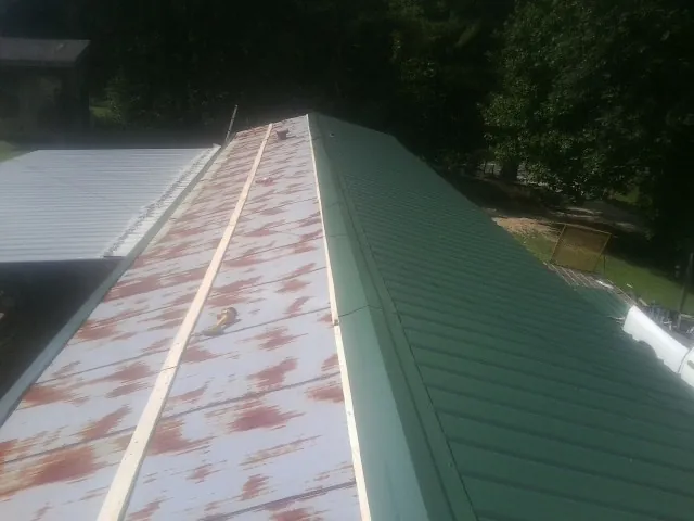 Old rusted panels beside newly installed green metal roofing — Wind Damage Roof Repair by Roofing Brothers in Roswell
