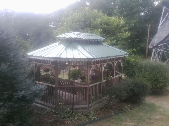 Green metal roof on a backyard gazebo surrounded by garden beds in Roswell
