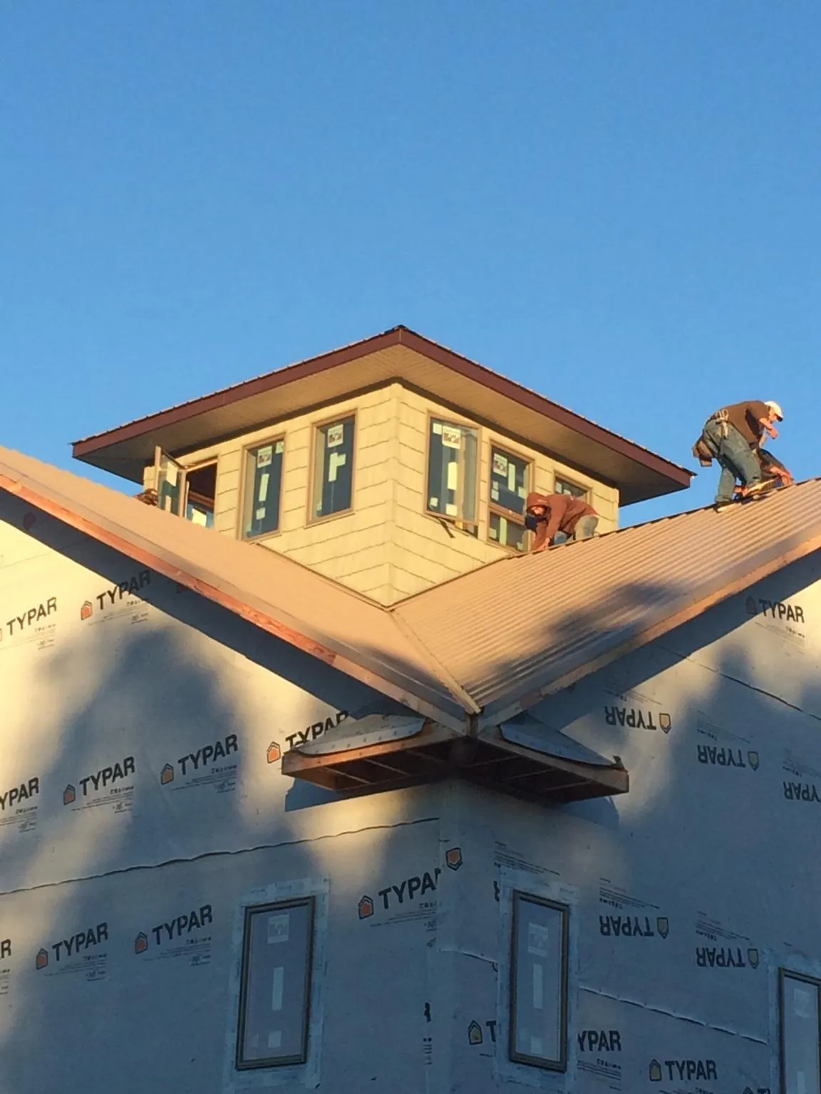Roofers working around a rooftop cupola on a new metal roof at sunset — Roof Waterproofing in Roswell by Roofing Brothers